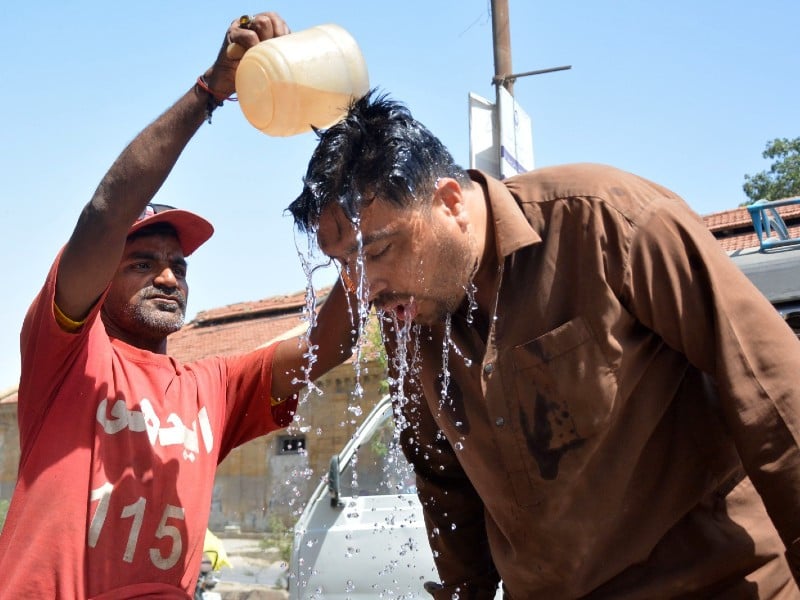 an edhi volunteer is offering water to a passer by providing relief from the scorching heat in front of the edhi centre in karachi s tower area on april 29 2024 photo express